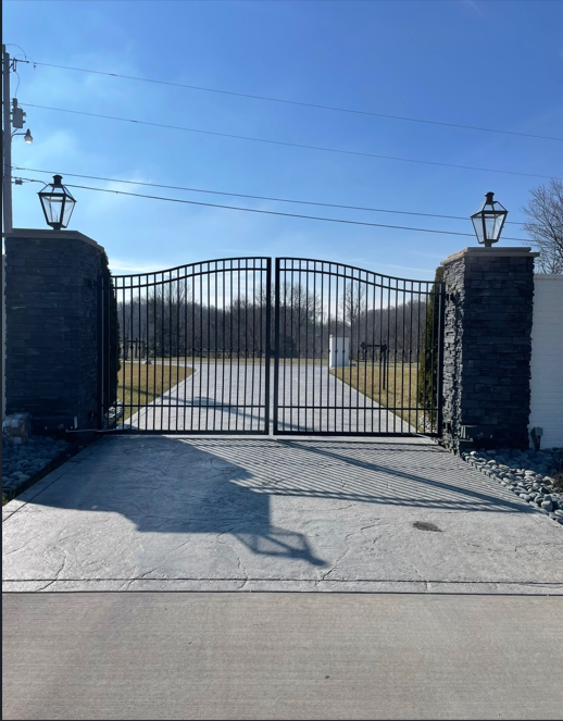 Black ornamental iron gate with stone columns and gas lanterns