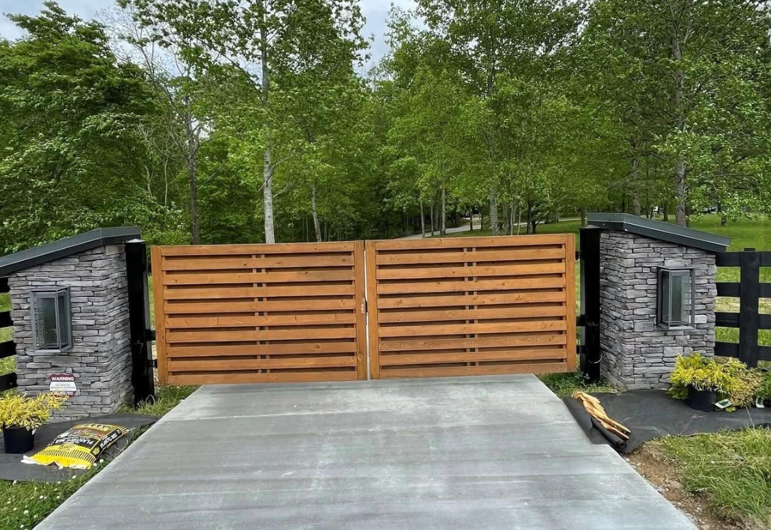 Modern horizontal slat wooden driveway gate with stone pillars