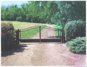 A driveway with a gate and trees in the background.
