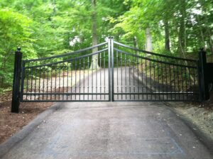 A driveway with two gates open and trees in the background.