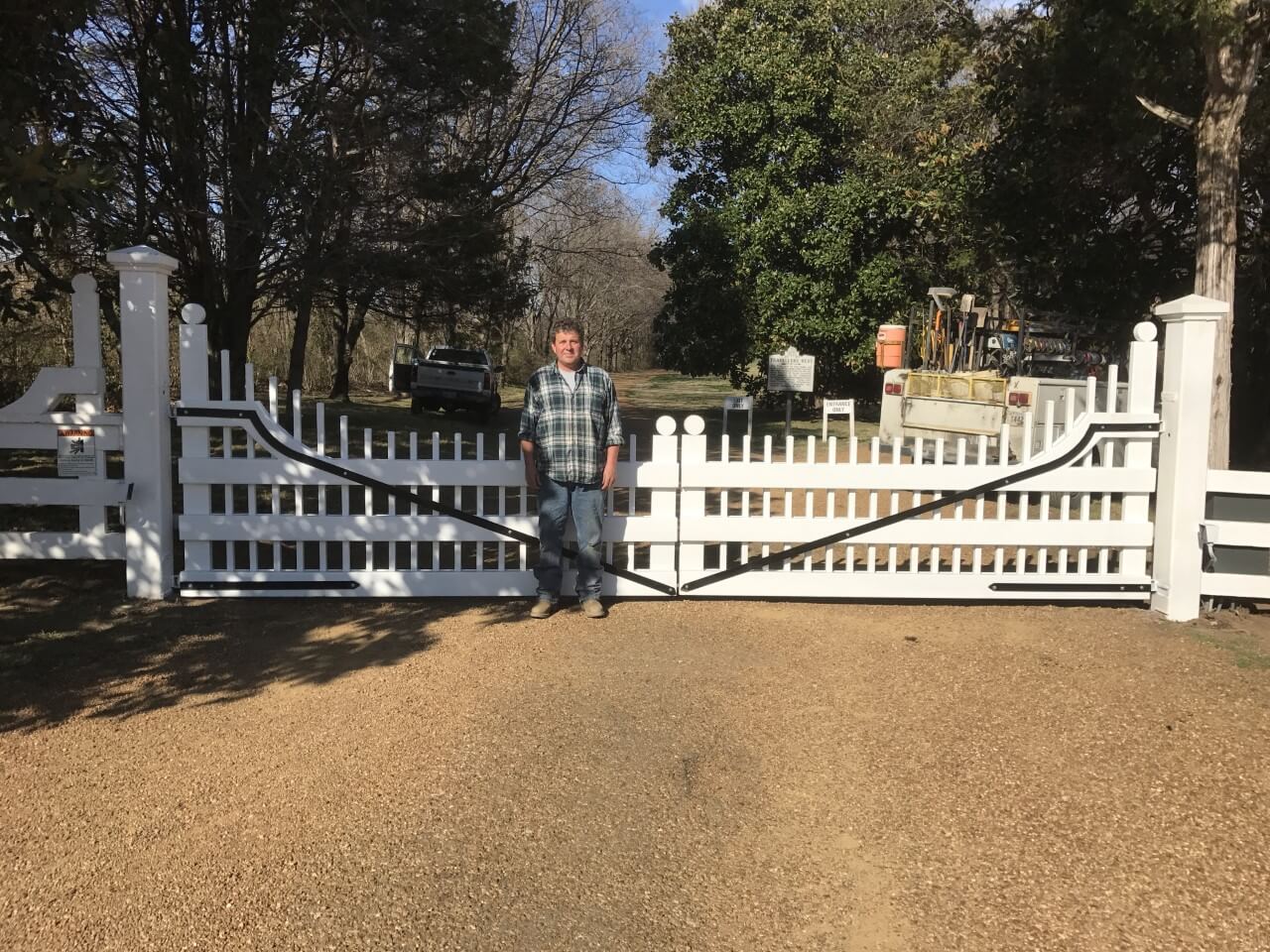 A man standing in front of a white fence.