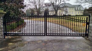 A driveway with two gates open and trees in the background.